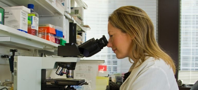 Žena laboratorijski tehničar analizira urin pomoću mikroskopa