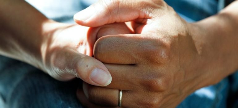 Zdrava osoba drži bolesnu za ruku.