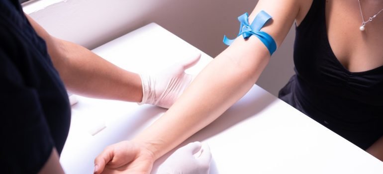 Laboratorijski tehničar vadi krv pacijentu.