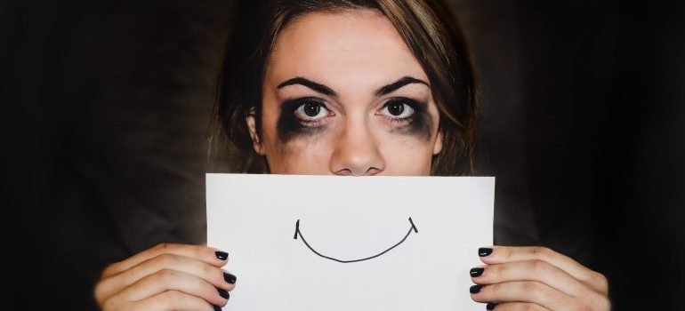 Depresivna osoba drži crtež smajlija preko usta