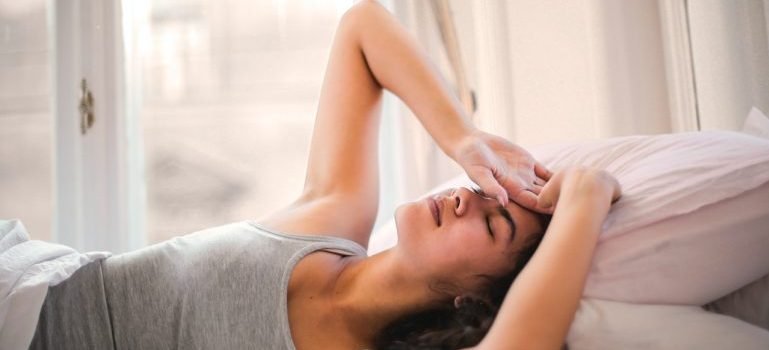 Žena se hvata za glavu dok leži u krevetu zbog glavobolje