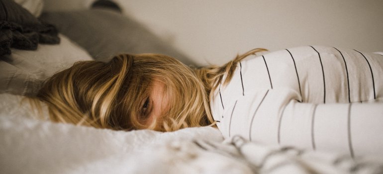 Žena koja je legla na krevet u odeći zbog umora.