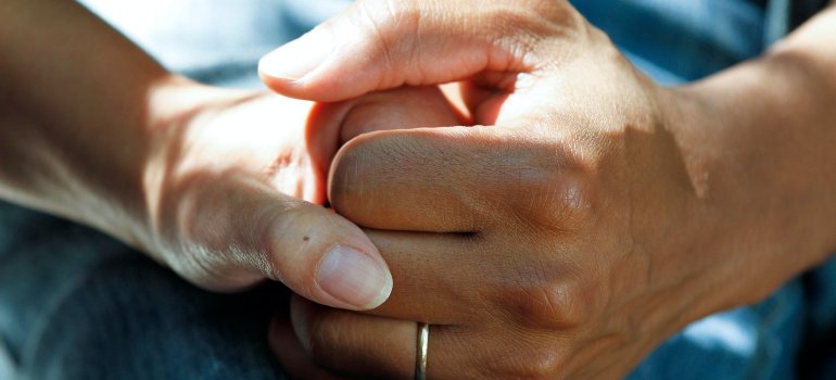 Jedna osoba drži drugu za ruku u znak podrške.