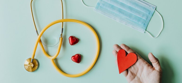 Slika sa maskom, stetoskopom i srcem koje drži osoba koja služi kao vizuelna reprezentacija teme šta je CRP i zašto je važan za dijagnostiku