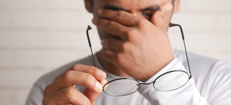 Osoba se drži za glavu zbog bola koji je verovatno povezan sa naočarama.