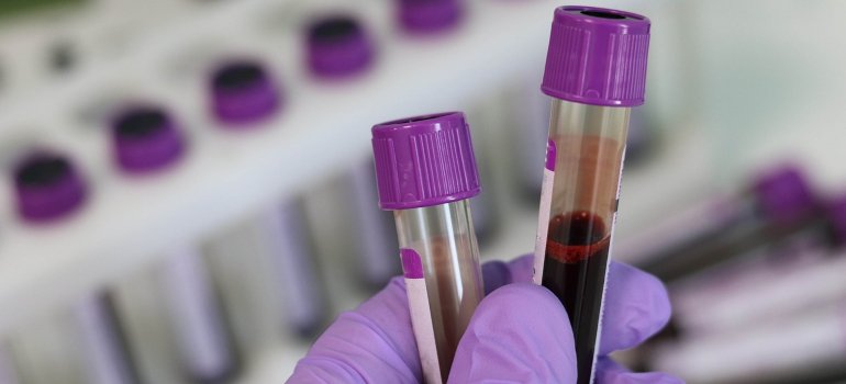 Laboratorijski tehničar drži dve upruvete sa krvlju.