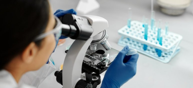 Laboratorijski tehničar ispituje nešto uz pomoć mikroskopa.