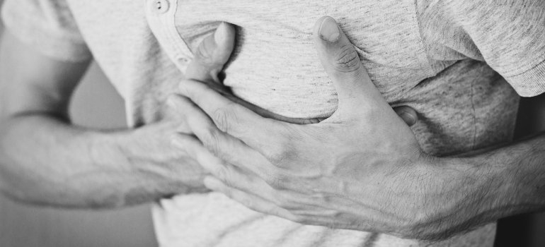 Čovek sa anginom pektoris se drži za grudi i služi kao primer zašto je važno redovno proveravati holesterol