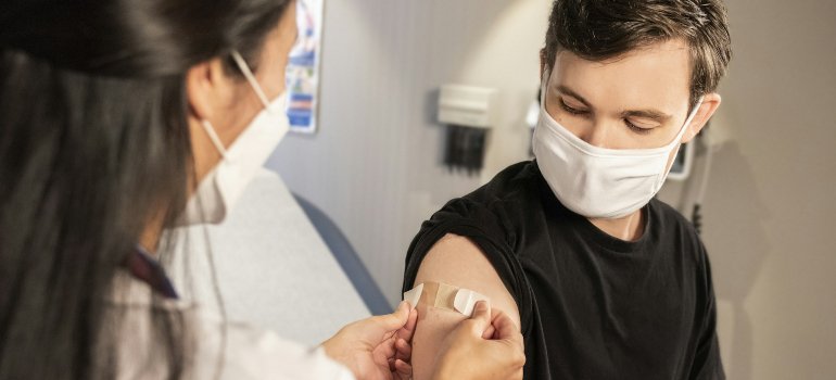 Женщина-врач наклеивает пластырь на плечо мальчику, который только что получил прививку от ВПЧ.