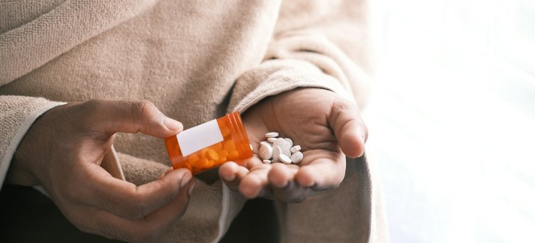 Osoba istresa tablete iz bočice u šaku