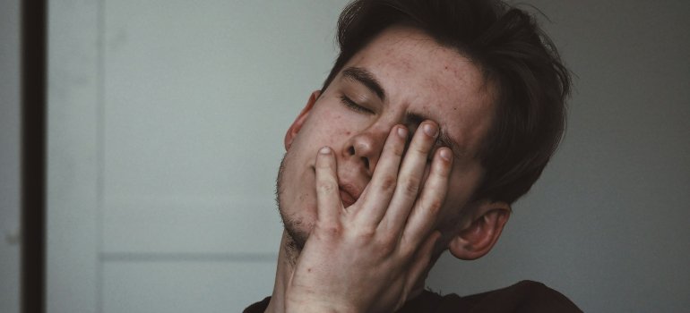 Umorni muškarac drži ruke na licu