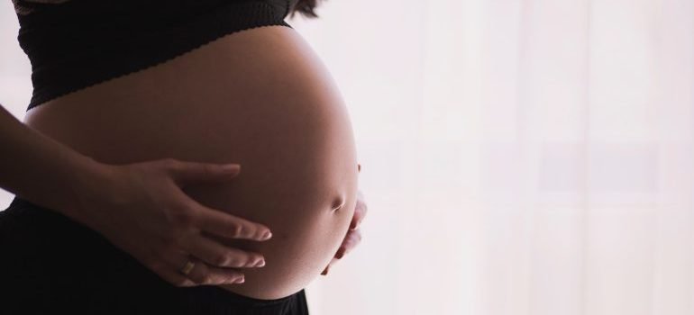 A pregnant woman holding her belly, prepared for pregnancy monitoring tests.