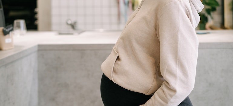 Беременная женщина в белой толстовке