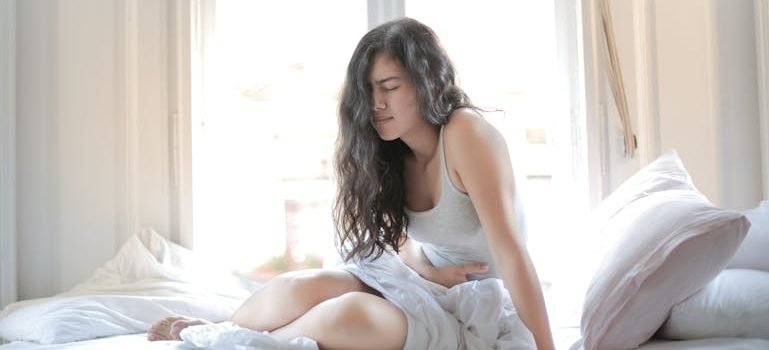 Женщина, которая держится за живот из-за болей, вызванных усиленным выделением желчи при беременности.