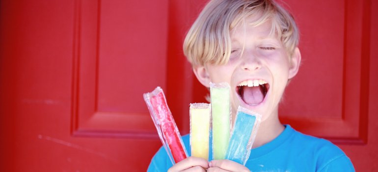 Дет широко улыбается, держа в руке леденец