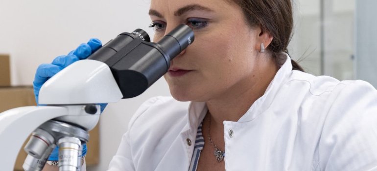A geneticist analyzing the sample using a microscope conducting Thrombophilia Factors analysis