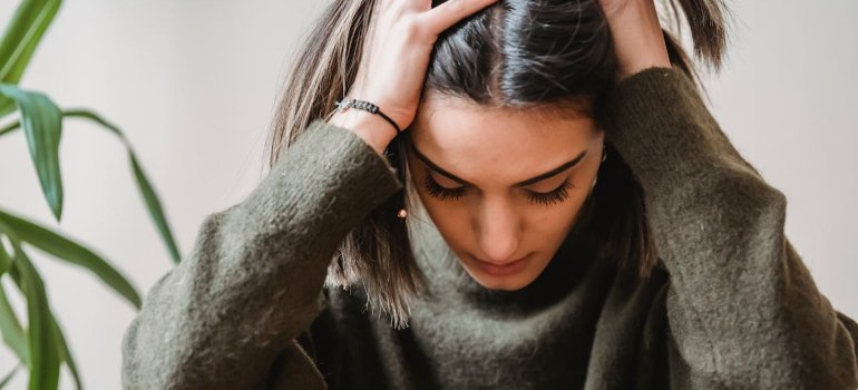 Женщина, у которой болит голова и из-за этого держится за голову