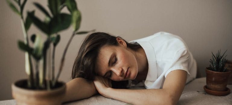 Уставшая женщина опирается на стол