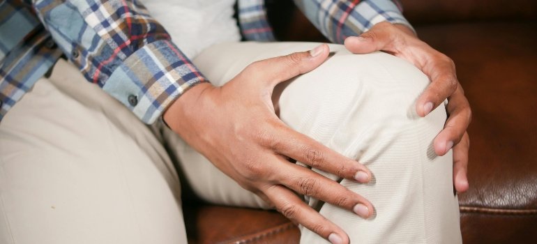 Osoba koja drži ruku na kolenu predstavlja reumatoidni artritis