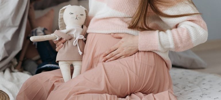 A pregnant woman holding a doll.