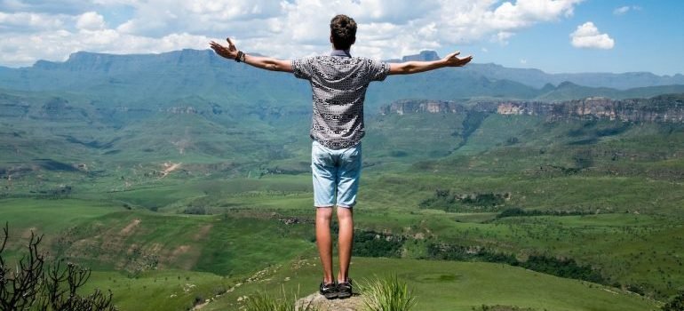 A person living life to the fullest stands on the edge of a mountain.