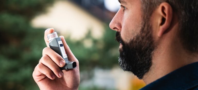 Мужчина использует ингалятор, у него астма и аллергический ринит.