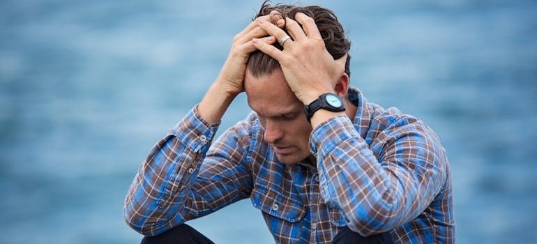 мужчина держится за голову, потому что стресс влияет на организм