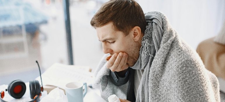 Человек, укрытый одеялом, кашляет и задаётся вопросом — отличается ли бронхит у детей и взрослых