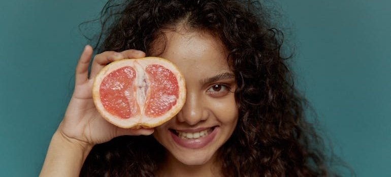 Женщина держит грейпфрут — возможный способ восполнить нехватку витаминов в организме.