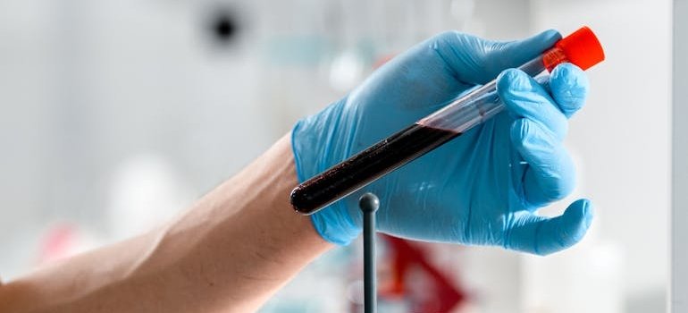 Человек держит пробирку с образцом крови