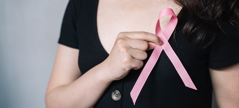 Женщина носит розовую ленту на одежде как знак поддержки осведомлённости о раке молочной железы.