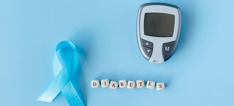 Глюкометр и голубая лента на столе, символ повышения осведомлённости о различных видах диабета.